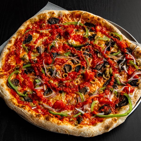 A whole vegetarian pizza with tomato sauce, green peppers, onions, mushrooms, and olives.